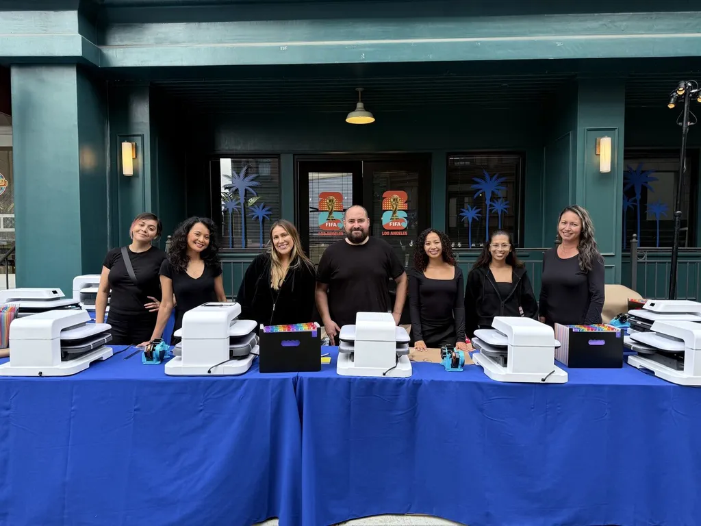 Merch Troop crew beside tabletop customization equipment